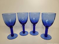 Four vintage blue wine glasses side by side showing gradient color swirl from light to dark blue with no chips or cracks.
