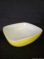 Square yellow Pyrex mixing bowl showing white interior, square shape with gently rounded corners.