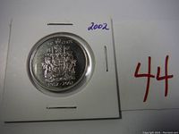 Reverse of Canadian 50 cent coin showing coat of arms and date 1952-2002 in holder labeled '2002'.