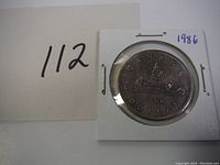 Front side of 1986 Canadian dollar coin showing the canoe design with paddlers and Northern Lights.