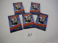 Five unopened 2006-07 Upper Deck Victory hockey trading card packs arranged flat with a card numbered 163 in front.