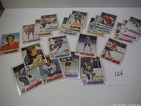 Photo showing multiple vintage 1977 OPC hockey cards, including Mike Milbury and other players from various NHL teams laid out on a white surface.
