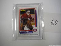 Front of Patrick Roy rookie hockey card with embedded piece of Sher-Wood goalie glove inside card encased in protective plastic.