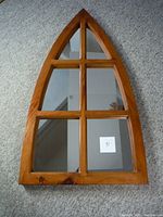 Arched wooden framed mirror with six divided glass panels, placed on carpet.
