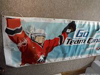 Close-up image of banner corner showing hockey player in red Team Canada jersey and 'Go Team Canada' text with hanging rope and metal grommets.