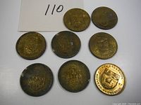 Eight vintage medallions showing Canadian provincial flowers and coats of arms in various conditions with tarnish and wear.