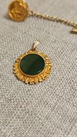 Close-up of the 10k gold necklace pendant with green jade stone, showing detail of the stone and gold setting.