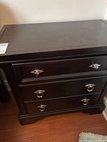 Full view of the bedside table showing the front with three drawers and ring pull handles.