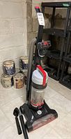 Front and side view of vacuum cleaner upright with hose and accessories attached and set beside the unit.
