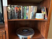 Shelf with boxed DVD collections of James Bond Ultimate Edition Volumes 1-4, CSI, NCIS DVDs, and blank DVD-R spindle.