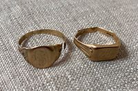 Front view of two signet rings showing oval and cushion bezels, monogram, engraving, broken bands