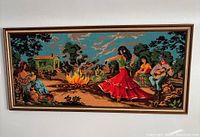Frontal image of the large needlepoint artwork showing the full scene with dancer, musician, and campfire.