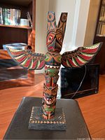 Front view of painted wood totem carving on square base