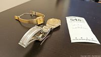 Two Seiko watches positioned next to auction lot tag on a black surface