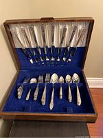 Photo of entire cutlery set in wooden case showing knives in satin holder and other cutlery in blue velvet slots