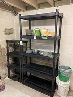 Photo of two black plastic utility shelves in basement corner, showing full height and tier design.