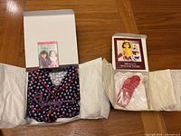 Full view of robe expanded out on table, slippers visible in the open box behind it, displaying complete condition and presentation.