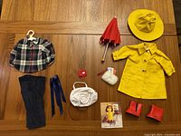 Full lot of American Girl Doll collectible accessories including clothing and accessories shown on wooden table, items separated in two groups.