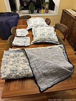 Full set on table showing comforter folded to display striped and beach motif sides, four pillow cases folded neatly.