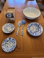 Arranged set of enamelware pieces on table with box of salad bowls.
