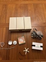 Photo showing all items: white jewelry box with compartments, silver heart charm bracelet, clear heart-shaped case, Herend porcelain bunny container, coral bead necklace, starfish, new Lafco bar soap, Michel Design Works Nutcracker-themed soap dish with shea butter soap.