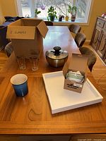 Wide shot of the lot contents on a wooden table, showing glasses, salad spinner, utensil holder, salad bowls in box, and tray.
