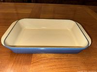 Side view of blue enameled cast iron roaster showing depth and interior cream enamel