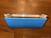 Side view of the blue exterior of the Le Creuset loaf pan showing its rectangular shape and handles.