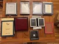 Collection of all eight frames and leather photo album laid out on table showing sizes, varied materials, and packaging.
