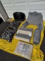 Lot displayed on yellow fabric outdoors including all described pillows, rug pad, lap desk and rug bag