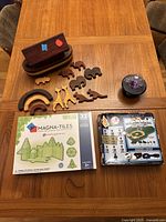 Photo of lot contents on table including wooden Noah's Ark figures, plasma ball, Magna-Tiles box, Yankees Game Time set
