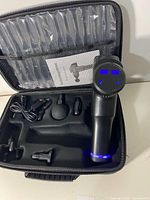 Top view of the massage gun in the carrying case with attachments and blue LED display active.