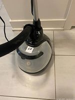 Top view of black and gray cloth steamer base with transparent water reservoir and power cord.