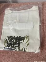 Folded white ladies T-shirt with printed leaves, sealed in plastic bag, showing front print.