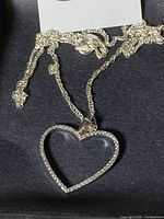 Close-up photo of the silver heart-shaped pendant with clear stones on a chain with spring ring clasp.