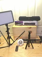 Photo showing LED video light on tripod stand, starry projection light, two tripods, remote control, and Bluetooth soundbars with box