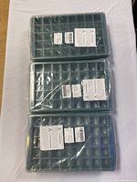 Top view of 3 stacked electric seedling planter trays in plastic wrap, showing individual compartments and labels.