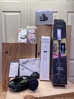 Photo showing the full lot including the GO VPRO LED light and tripod box, Sensyne Bluetooth selfie stick box, Lovmoofu phone case, wired Apple earbuds, HDMI cable labeled bag, Ethernet extension cable coiled, and a recessed outlet with USB ports.