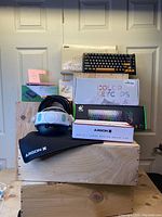 Full lot showing VR headstrap, keyboards, mouse pads, HDMI cable, charging accessories, and custom keycaps in boxes.