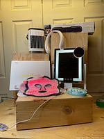 Full set of six items including LED face mask, vanity mirror, Bluetooth soundbar, neck fan, cooling fan, and electric nail file set displayed on wooden blocks against door background.