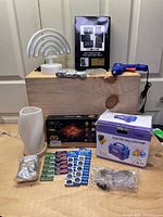 A photo showing the hot glue gun, mini chalkboard signs with marker, white textured lamp shade, lithium coin batteries, boxed electric balloon pump, and a light up star garland box.