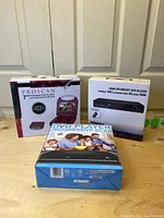 Photo showing 3 DVD players in original boxes: PROSCAN 7" Electronic DVD Portable Player, HDM Upconvert DVD player, and PROSCAN Progressive Scan DVD Player.