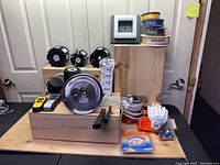 Wide view showing various renovation items including spools of wire, LED garage lights, power bars, paint roller, gloves, and small accessories.