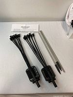 Solar garden lights with black stakes and two metal spike stakes laid on a white surface next to user manual.