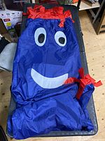 Inflatable mascot laid out, showing the blue body with red accents and white facial features including eyes and mouth.