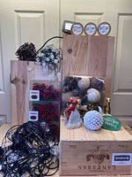 Various Christmas decorations and assorted lighting displayed on wooden crates including berry garlands, ornaments, lights and decoration figurines