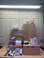 Photo of the HomeKit pet vacuum and trimmer with various grooming attachments and the Fluffyunion pet fountain on wooden risers, along with a colorful interactive cat toy.