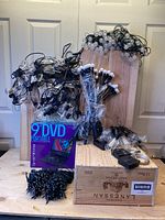 Photo showing multiple bundles of wired solar LED lights, black solar stakes with LED bulbs, and a boxed 9-inch portable DVD player.