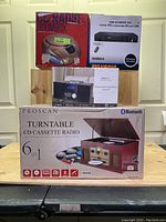 Photo showing stacked boxes of all items including the Proscan 6-in-1 turntable, Bluetooth CD micro system, CD radio boombox, and DVD player.