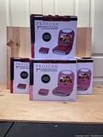 Four boxed Proscan 7-inch portable DVD players stacked on wood surface, two red and two pink units visible in packaging images, front view.